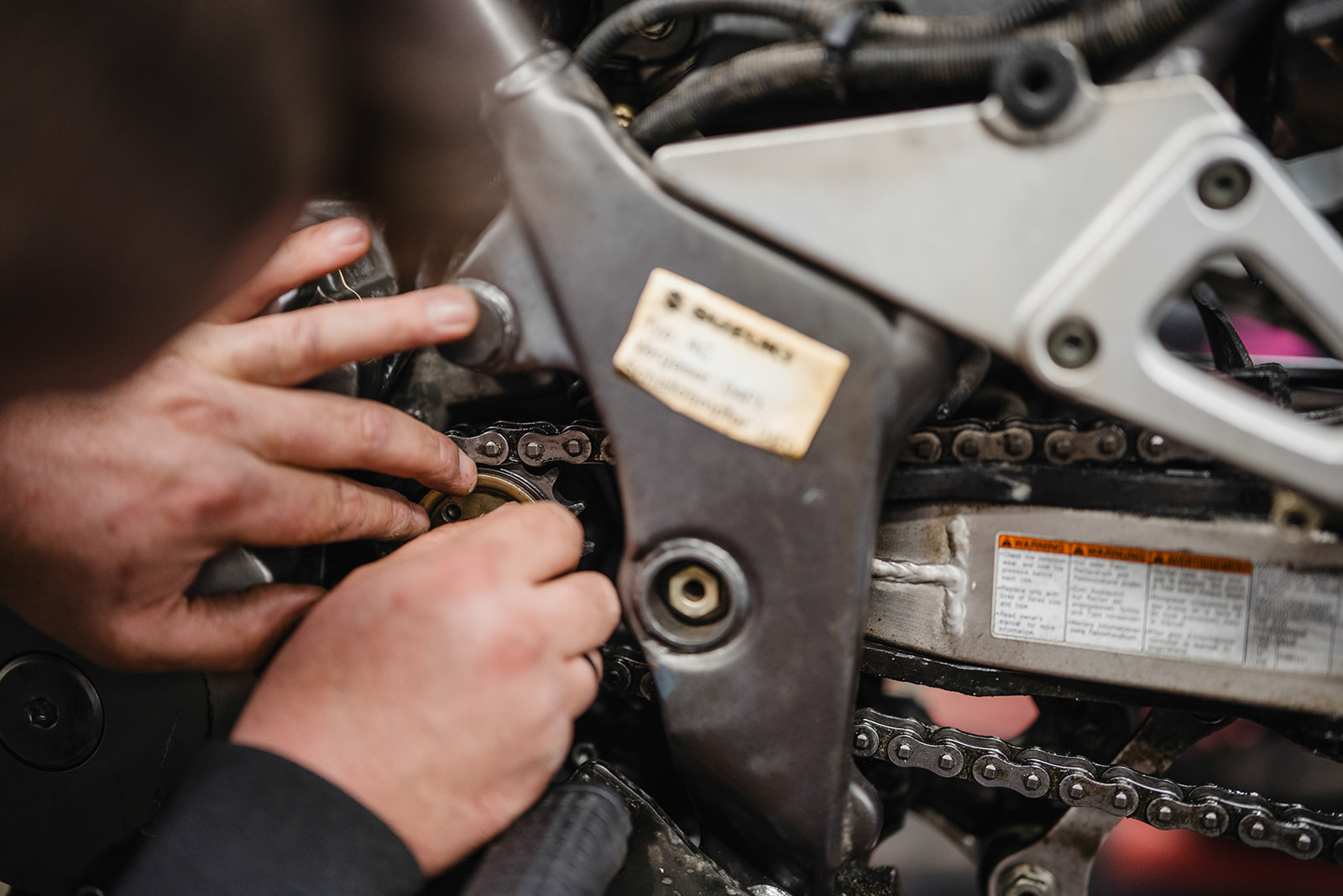 Mechaniker überprüft die Kette eines Motorrads beim Saisoncheck in der Werkstatt