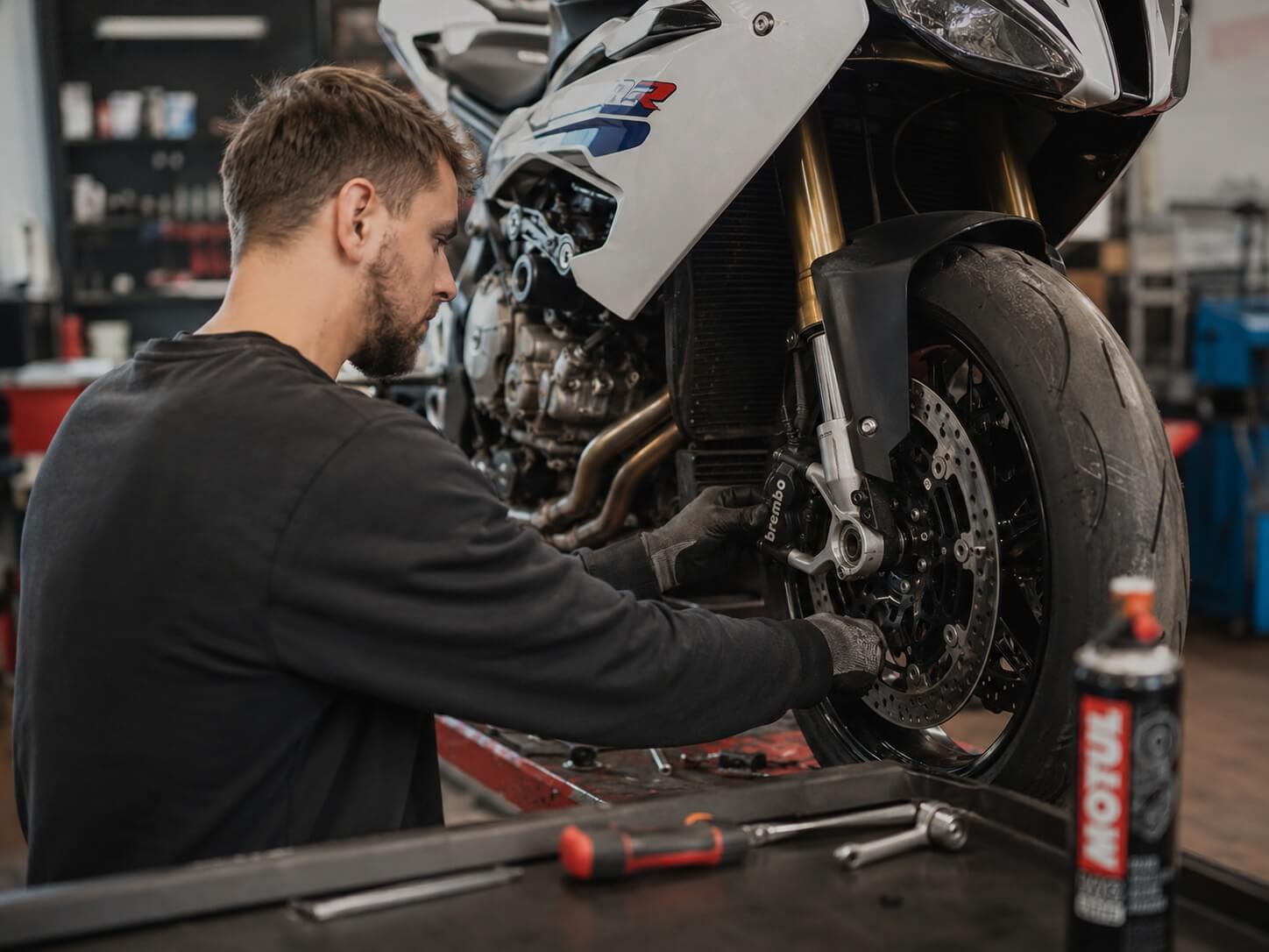 Motorrad-Saisoncheck für einen sicheren Saisonstart Motorrads Saisoncheck - Mechaniker überprüft die Kette in der Werkstatt