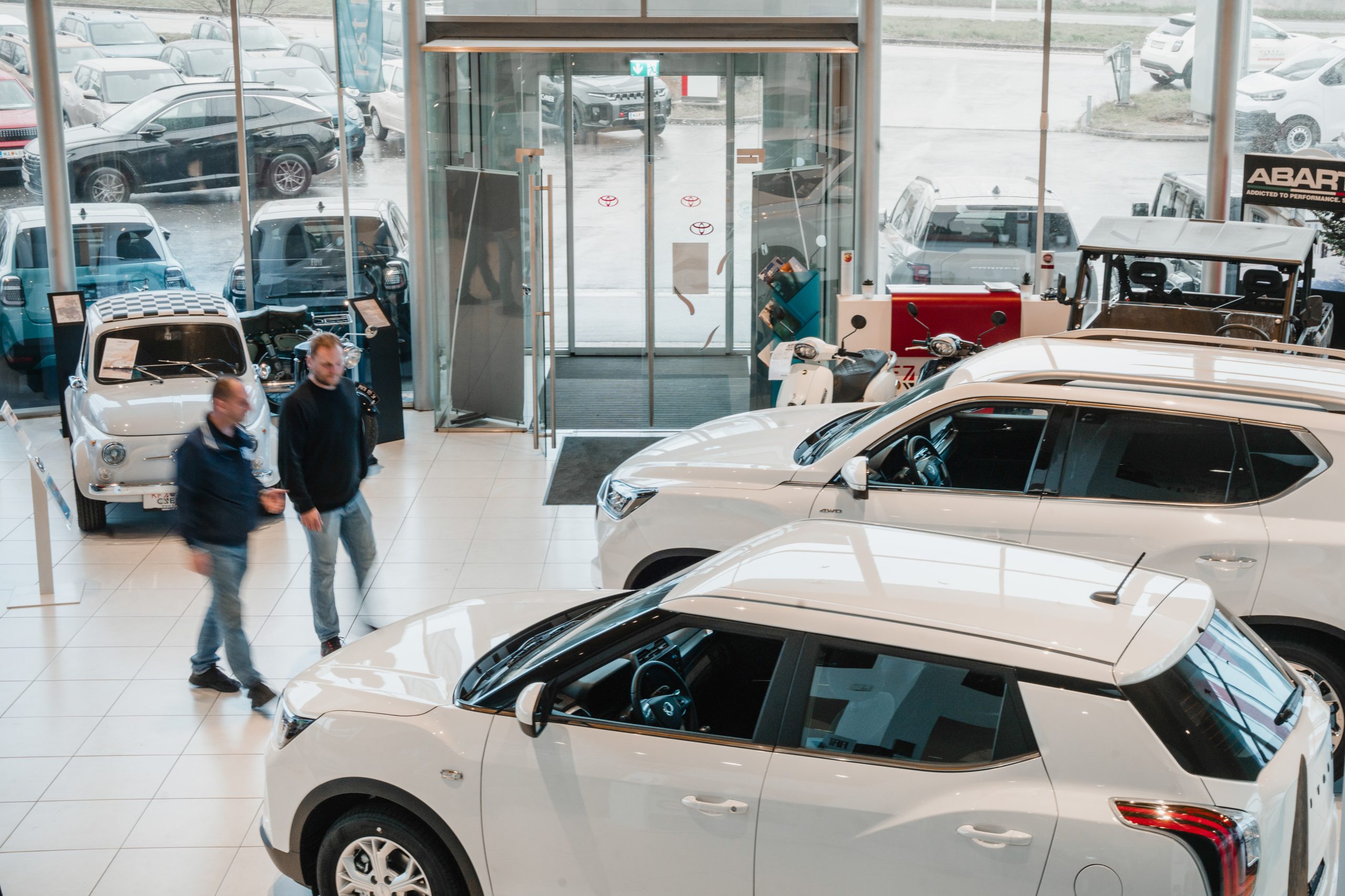 Blick in den hellen Schauraum eines Autohauses mit ausgestellten Fahrzeugen und Kundenbereich